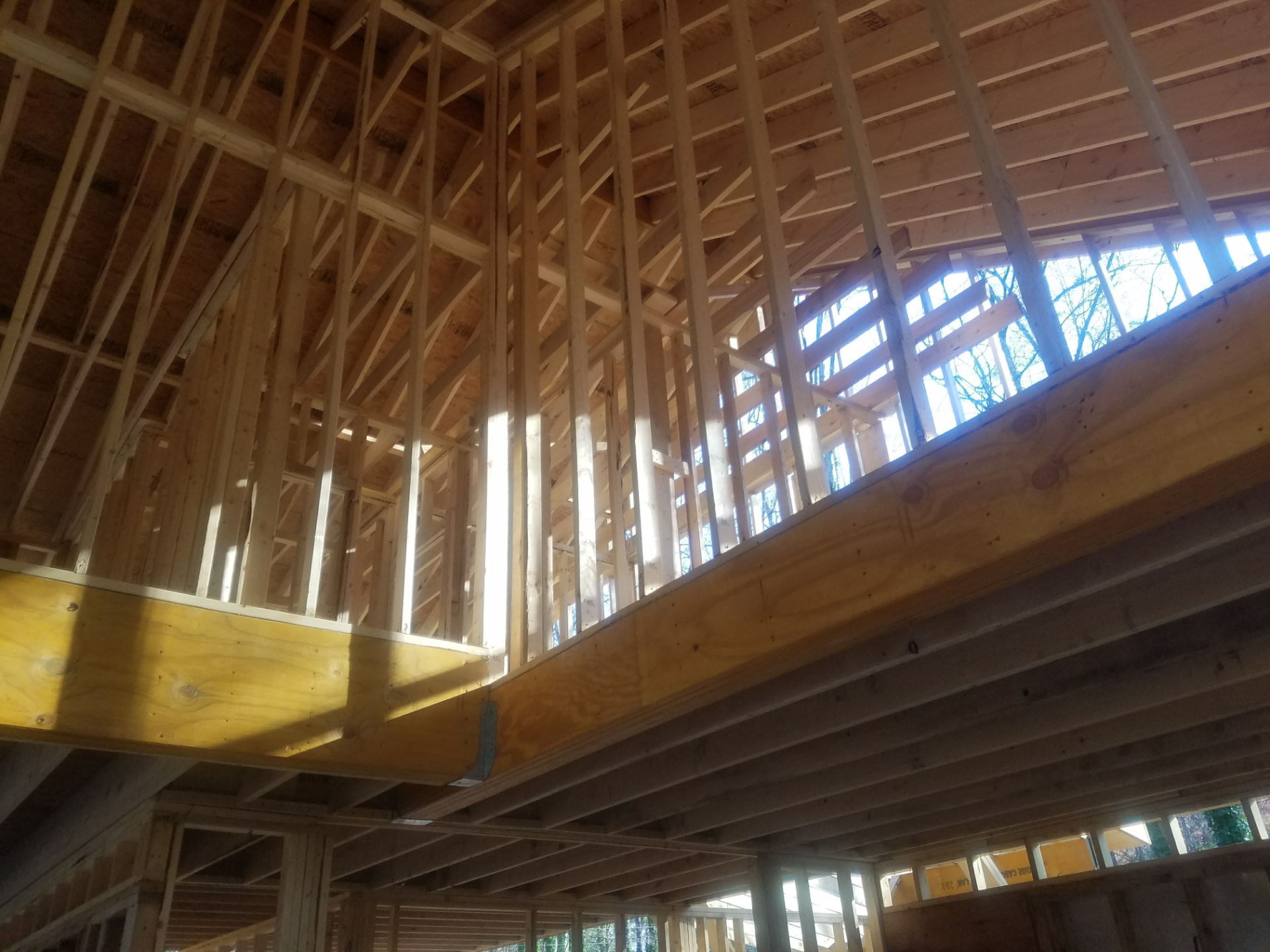 Vaulted great-room framing with engineered beams and rafters — a Statewide project