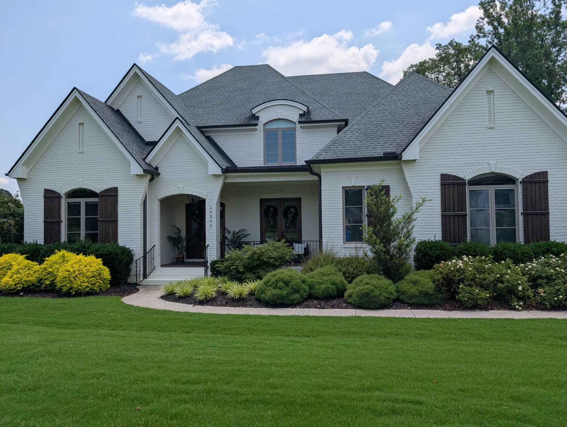 White brick home with a newly installed gray architectural shingle roof — a Statewide project