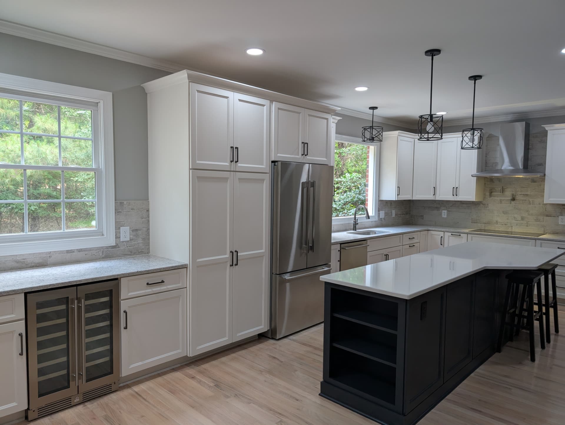 White paneled kitchen with a navy island and stone counters — a Statewide remodel